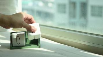 Hand changing white wooden calendar block from 8 to 9 video