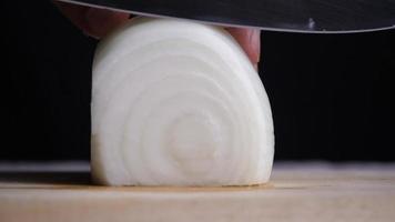 The chef uses a kitchen knife to slice a white onion video