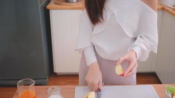 Mujer asiática corta una manzana roja y la muerde video
