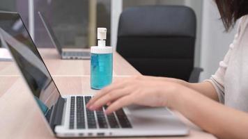 empresária digitando em um laptop e higienizando as mãos video