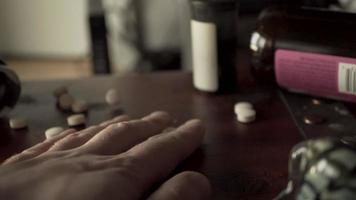 mão agarra comprimidos freneticamente em uma mesa de madeira video
