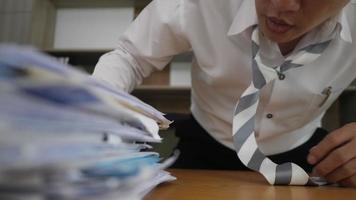 Overworked businessman looking at a stack of paper documents in hid office video