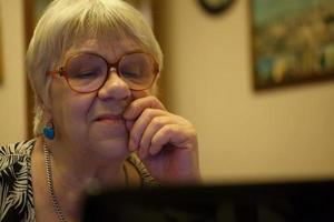 mujer mayor pensativa leyendo una pantalla de computadora foto