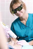 Smiling practitioner doing a laser treatment photo