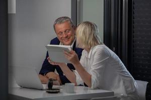 A middle-aged couple at the table with a tablet photo