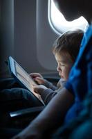 Little boy playing with a tablet in an airplane photo