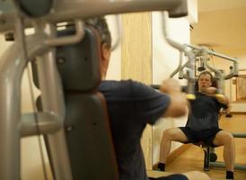 Mature man exercising on shoulder press machine photo