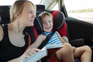 Mother reading a book to son in the car photo