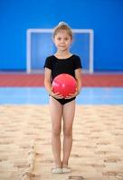 joven gimnasta sosteniendo una bola roja foto
