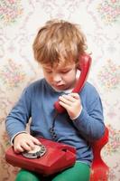 Small boy talking on a red telephone photo