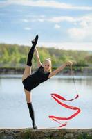 gimnasta adolescente haciendo una división vertical con una cinta foto