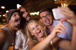 Young people having fun taking a selfie at night photo