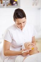 esteticista aplicando una mascarilla facial foto