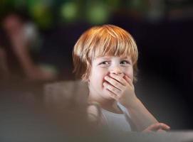 Young boy covering mouth photo