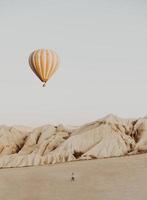 Person watching a white hot air balloon in the desert photo