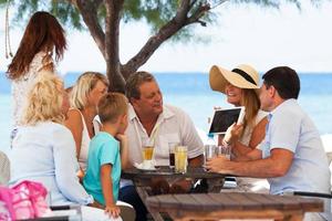 Family looking at photo on a tablet in an outdoor cafe