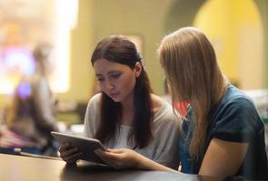 Two women in a restaurant using a tablet photo