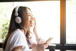 Mujer joven escuchando música en auriculares con fondo de ventana