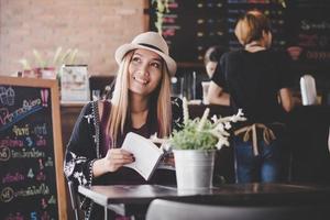 Happy business woman reading book while relaxing at cafe photo