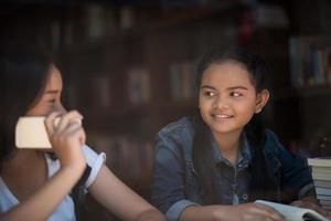 Mujeres jóvenes usando y mirando el teléfono inteligente en la cafetería de la ventana foto