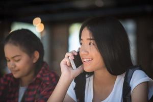 Mujeres jóvenes usando y mirando el teléfono inteligente en la cafetería de la ventana