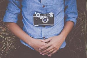 Young hipster woman with vintage camera lying down in field outdoors photo