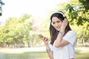 Portrait of a smiling girl with headphones listening to music in nature photo