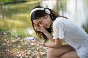 Retrato de una niña sonriente con auriculares escuchando música en la naturaleza