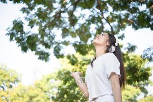 Retrato de una niña sonriente con auriculares escuchando música en la naturaleza foto