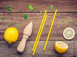 Fresh lemon, juicer and straws on a wooden background photo