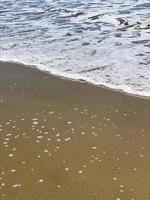 Foamy waves on a sandy beach photo