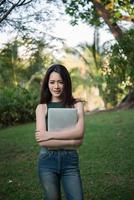 Young beautiful woman holding a laptop computer while going to relax at a park photo