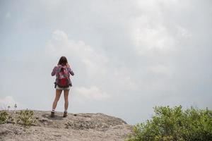 Caminante con mochila de pie en la cima de una montaña y disfrutando de la vista de la naturaleza foto