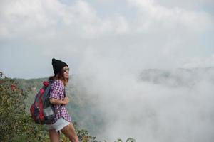 Hiker with backpack standing on top of a mountain and enjoying nature view photo
