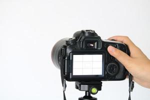 Hand adjusting DSLR camera from rear view on white background photo