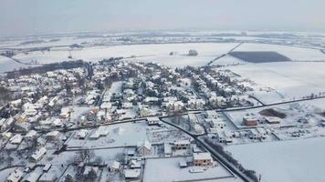 Flygfoto över en frusen snöig by på en solig vinterdag i 4k video