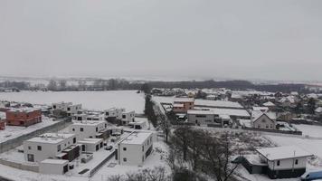 drone stigande över moln och vita snöiga hus i by med hus i 4k video