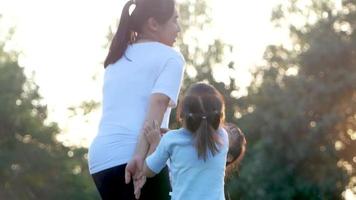 två små flickor och mamma som tränar tillsammans i en park. video