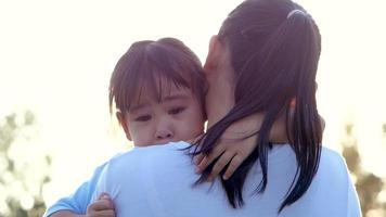 Mother comforting her crying little girl in an outdoor park.