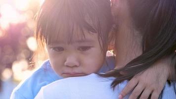 moeder troost haar huilende meisje in een openluchtpark. video