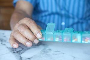 Senior man's hands taking medicine from a pill box photo