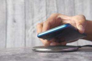 Hand charging a smartphone using wireless charging pad, top view photo