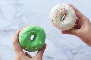 Woman's hand holding fresh donuts, close-up photo