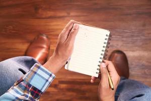 High angle view of a man sitting on a chair holding a notepad photo