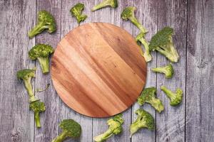 Slices of brocolli and chopping board on table photo