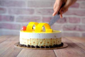 Close-up de una mano de mujer cortando un pastel de postre dulce foto