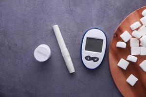 Herramientas de medición para diabéticos y terrón de azúcar sobre fondo negro foto