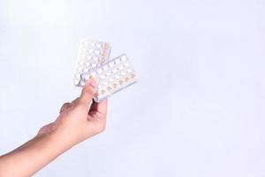 Mano de mujer sosteniendo píldoras anticonceptivas aislado sobre fondo blanco. foto