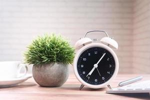 Tea cup, laptop and clock on table close-up photo