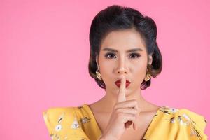 Asian woman with red lips and finger showing hush silence photo